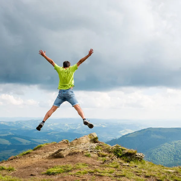 Homem pulando no pico da montanha — Fotografia de Stock