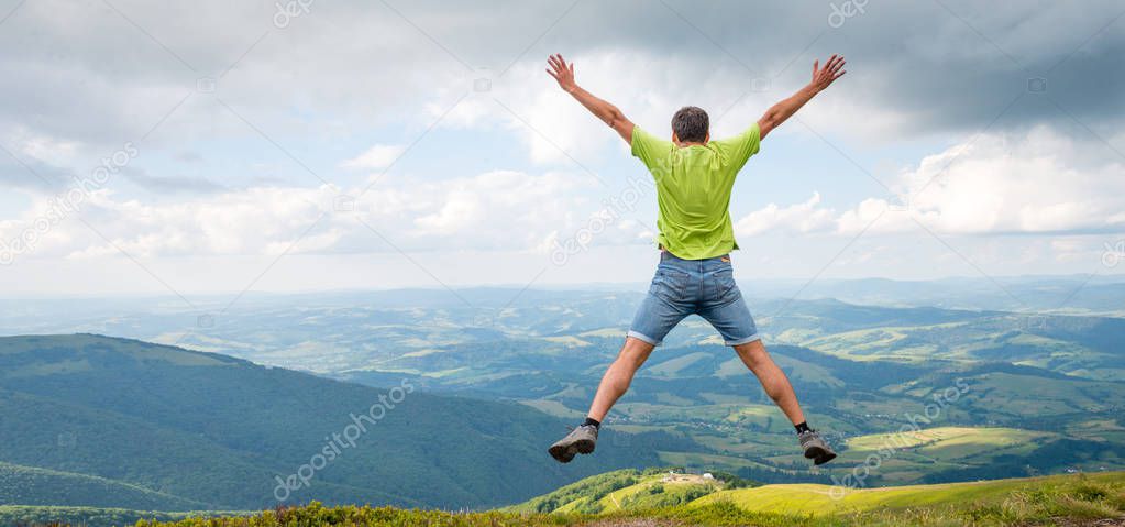 man jumping on the peak of the mountain