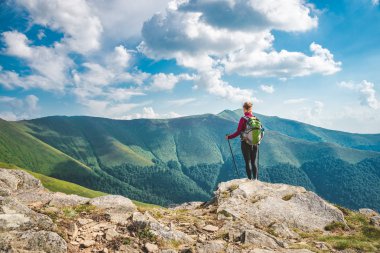 Sırt çantalı genç bir kadın dağda yürüyüş yapıyor.