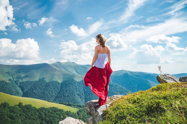 穿着红色连衣裙的年轻女子留在山顶上 — 图库照片