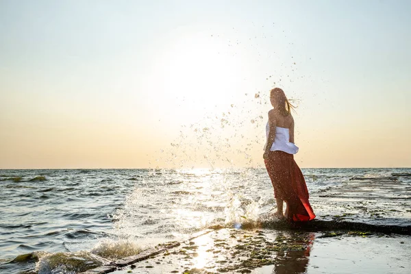 Vacker flicka i röd klänning vid havet. — Stockfoto