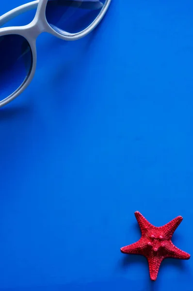Güneş gözlüğü ve denizyıldızı mavi bir arka plan üzerinde