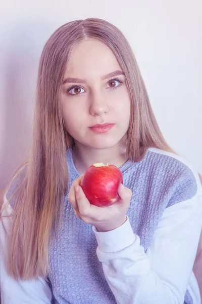 The girl is giving an apple with a bitten edge