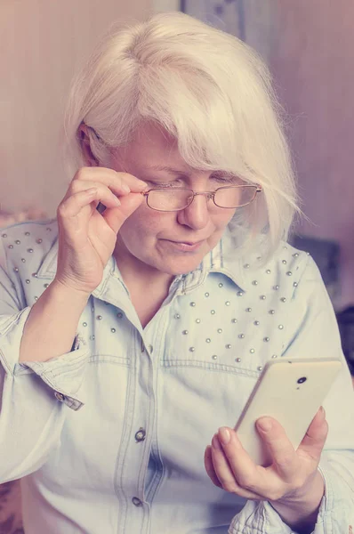 Kadın gözlük ile sağ elini tutar ve telefon sol elini tutar