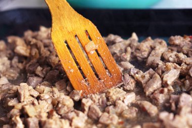 Birisi bir tahta spatula ile fırın tepsisine güveç kıpırdanırken