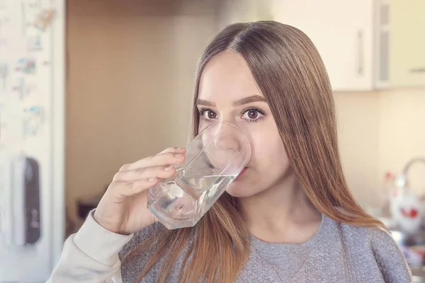 Bir genç kız mutfakta cam suyu içer
