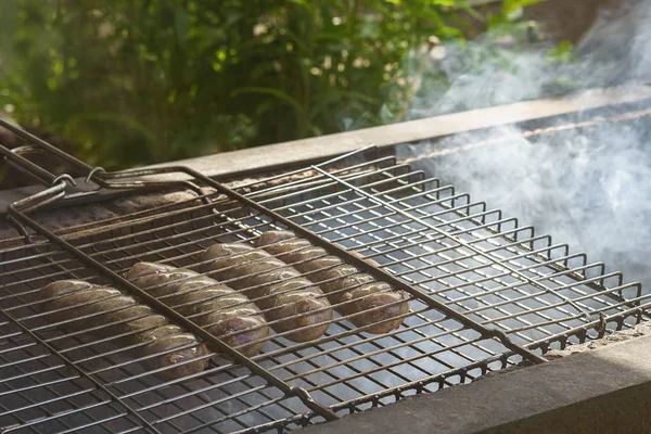 Sausages are fried on fire, smoke is coming