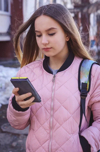 Saç uçan ile bir kız sokakta duran ve seyir telefon
