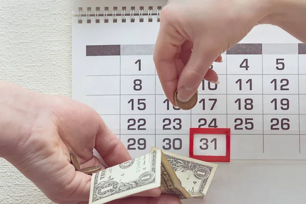 People transfer money to each other on the background of a calendar with the highlighted date 31