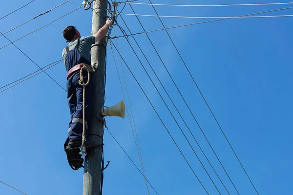 Bir elektrikçi ahşap direğe telleri tamir tepesinde olduğunu
