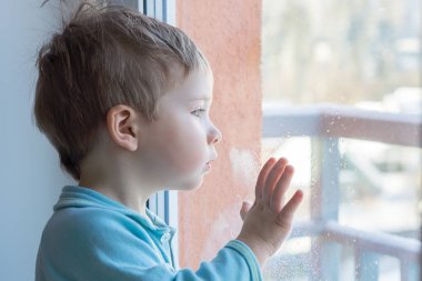 Çocuk elini pencere camı koydu ve pencereden dışarı bakmak için sürpriz