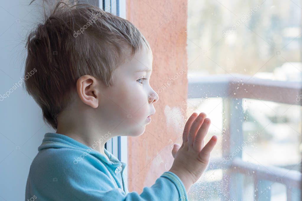The child put his hand on the windowpane and is surprised to look out the window