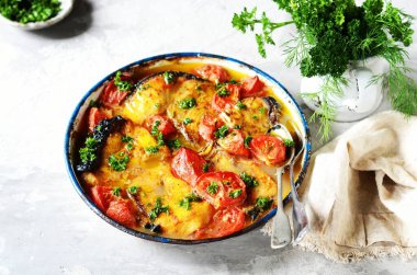 Fırınlanmış balık (köpekbalığı) domates ve baharatlarla gri arka planda pişirme kabında, durgun yaşam