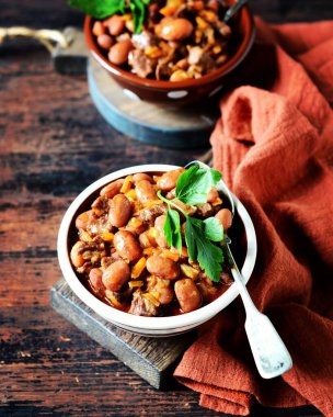 Siyah ahşap arka planda fasulyeli, domatesli ve sebzeli biftek yahnisi.