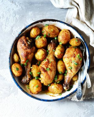 Fırında tavuk budu ve gri arka planda fırında patates.