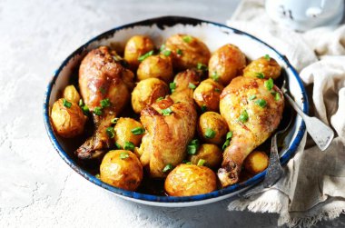 Fırında tavuk budu ve gri arka planda fırında patates.