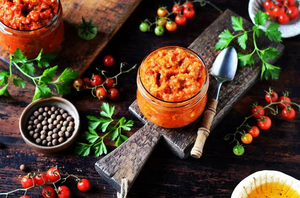 Eggplant caviar with vegetables in glass jars on a dark wooden table