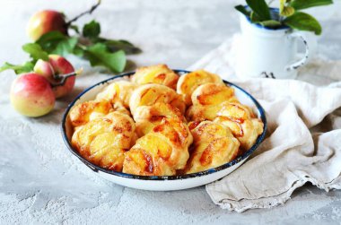 Gri arka planda bir kasede karamelli elmalı krep.