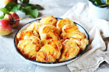 Gri arka planda bir kasede karamelli elmalı krep.