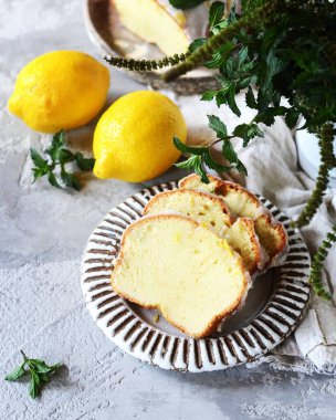 Lezzetli ev yapımı limonlu pasta, tabakta krema ve gri bir arka plan.