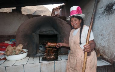 Cuzco, Peru - August 13 2011: A peruvian cook and the oven. Showing a roasted cuis. clipart