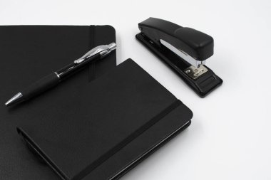 siyah deri Not defteri, kalem ve beyaz arka plan üzerinde zımba. Masaüstü Seti. Ofis masaları. İşe geri.