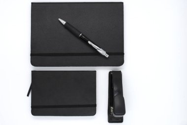 siyah deri Not defteri, kalem ve beyaz arka plan üzerinde zımba. Masaüstü Seti. Ofis masaları. İşe geri.