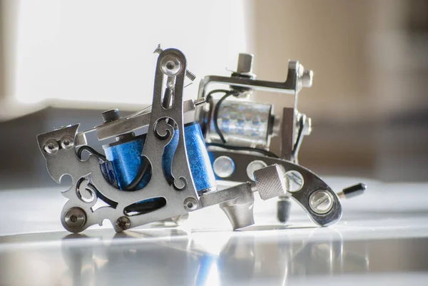 Tattoo machines isolated on calico background. one metal another blue. Tattoos