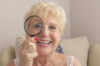 Görme sorunları olan üst düzey kadın ve büyüteç gülümseyen.