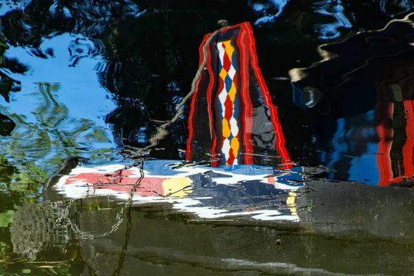 Reflections of a canal, or narrow, boat moored on a summers day on the River Stort in Sawbridgeworth in Hertfordshire