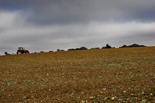 A farmer tills a field on a hill in Lower Sheering Essex.  Late autumn and rain is expected.