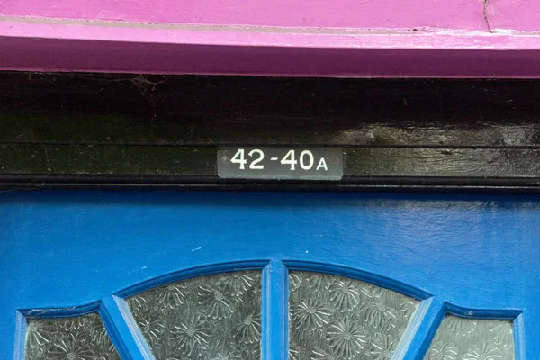 The house number 42 and 40A on a black, blue, and purple painted door frame in Hertfordshire.
