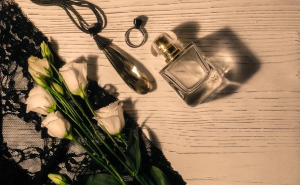 Still life with roses,pendant,ring and perfume on white wooden background.