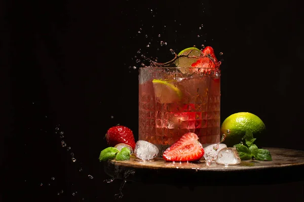 Cocktail rinfrescante con fragole, lime, foglie di menta, acqua e cubetti di ghiaccio sul tavolo di legno.. — Foto Stock