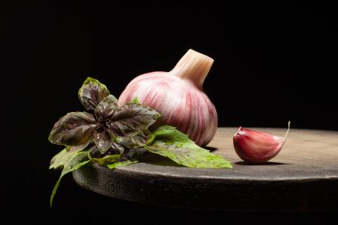 Taze sarımsak ve mor fesleğen siyah arka plandaki ahşap masada. Baharat malzemelerini kapatın..