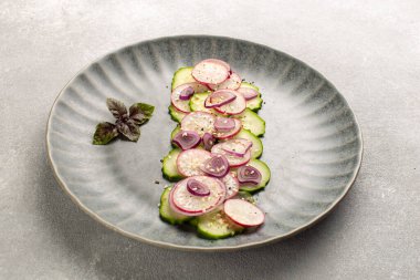 Turp salatalı taze salata, kırmızı soğan, susam tohumu ve gri seramik tabakta mor fesleğen yaprağı. Vegan yaz salatası..