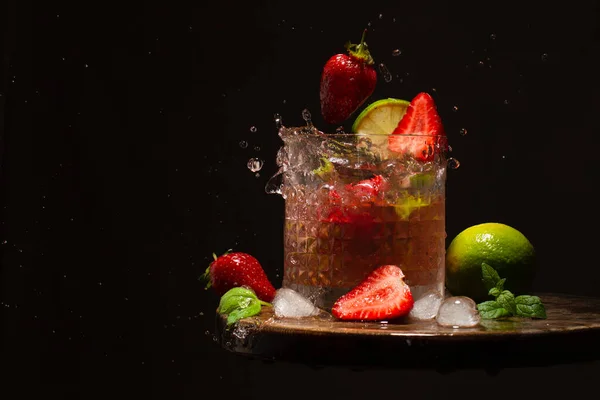 Cocktail rinfrescante con fragole, lime, foglie di menta, acqua e cubetti di ghiaccio sul tavolo di legno.. — Foto Stock