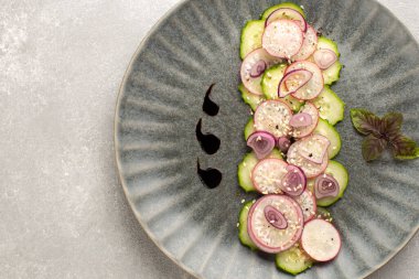 Turp salatalı taze salata, kırmızı soğan, susam tohumu ve gri seramik tabakta mor fesleğen yaprağı. Vegan yaz salatası..
