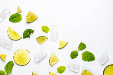 Taze limon dilimleri, nane yaprakları, buz küpleri ve su damlalarıyla beyaz ferahlatıcı gıda arka planı..