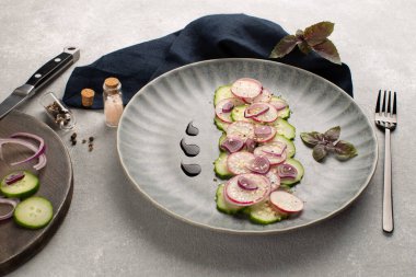 Turşulu taze salata, kırmızı soğan, susam tohumu ve gri seramik tabakta mor fesleğen yaprağı. Vegan yaz salatası..