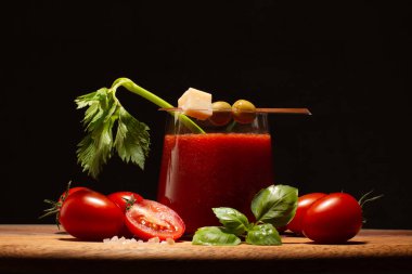 Taze kereviz dalıyla taze domates suyu, fesleğen yaprağı, yeşil zeytin, parmesan peyniri ve ahşap masada domates. Sağlıklı içeceğe yakın..