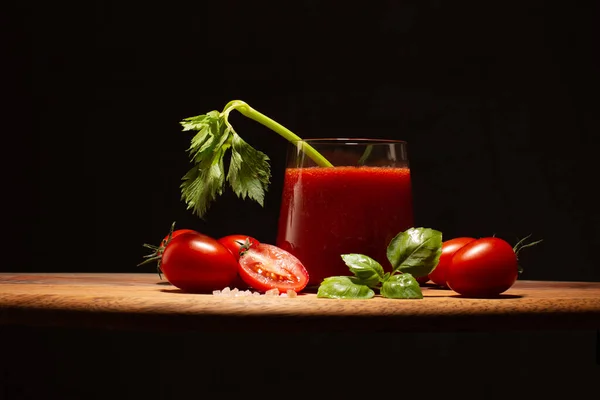 Fresh tomato juice in a glass with branch of fresh celery,basil leaves and tomatoes on wooden table.Close up of healthy drink. — Stock Photo, Image