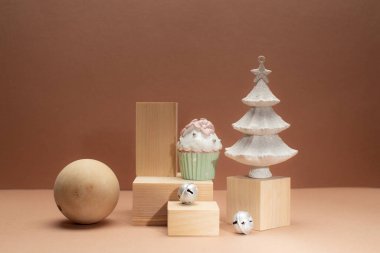 Kavramsal moda Noel ya da yeni yıl kartı ahşap podyumlar, ahşap top, Hristiyan ağacı ve tek renkli bej arka planda Noel çanları.