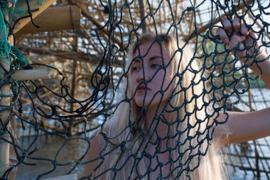 Bir ızgara ile bir kafes içinde denizde kırmızı mayo Blonde