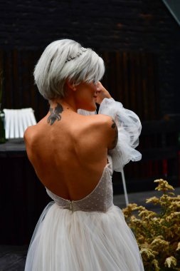 Beyaz elbiseli, sırtı çıplak ve dövmeli güzel sarışın gelin.