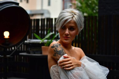 Beyaz elbiseli, sırtı çıplak ve dövmeli güzel sarışın gelin.