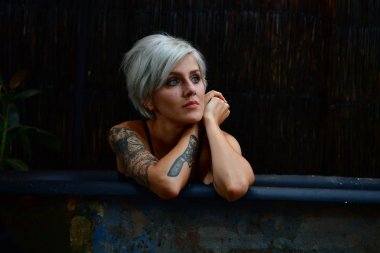 beautiful short-haired girl with tattoo posing in bath. romance.