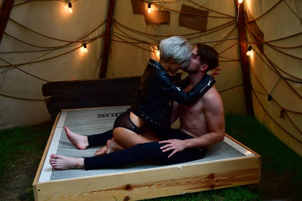 Flicka och kille leker på en säng i ett tält med kransar i romantik — Stockfoto