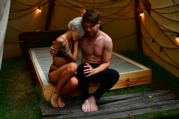 Flicka och kille leker på en säng i ett tält med kransar i romantik — Stockfoto