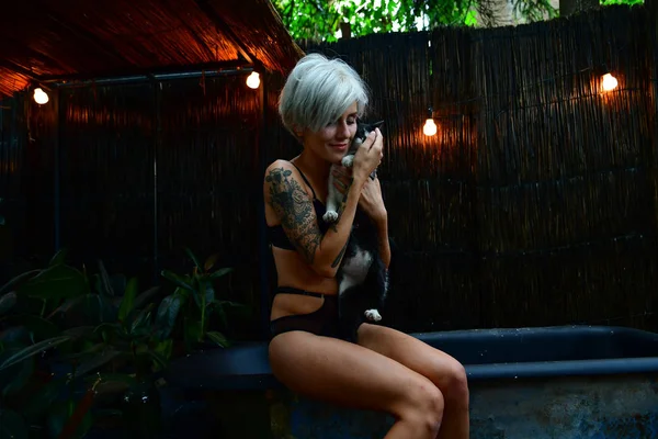 Retrato de bela jovem mulher sentada no banho segurando um gato — Fotografia de Stock